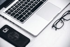 A picture of a laptop, a smartphone, and glasses.